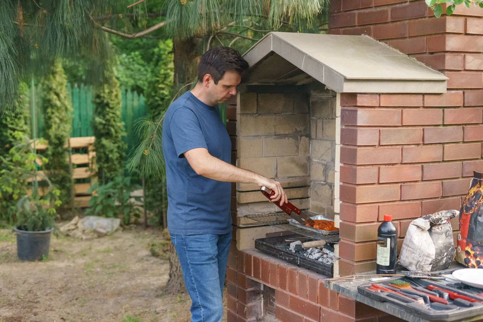 Barbecue en pierre maçonné dans un jardin, plan de travail en pierre naturelle et grille en fonte